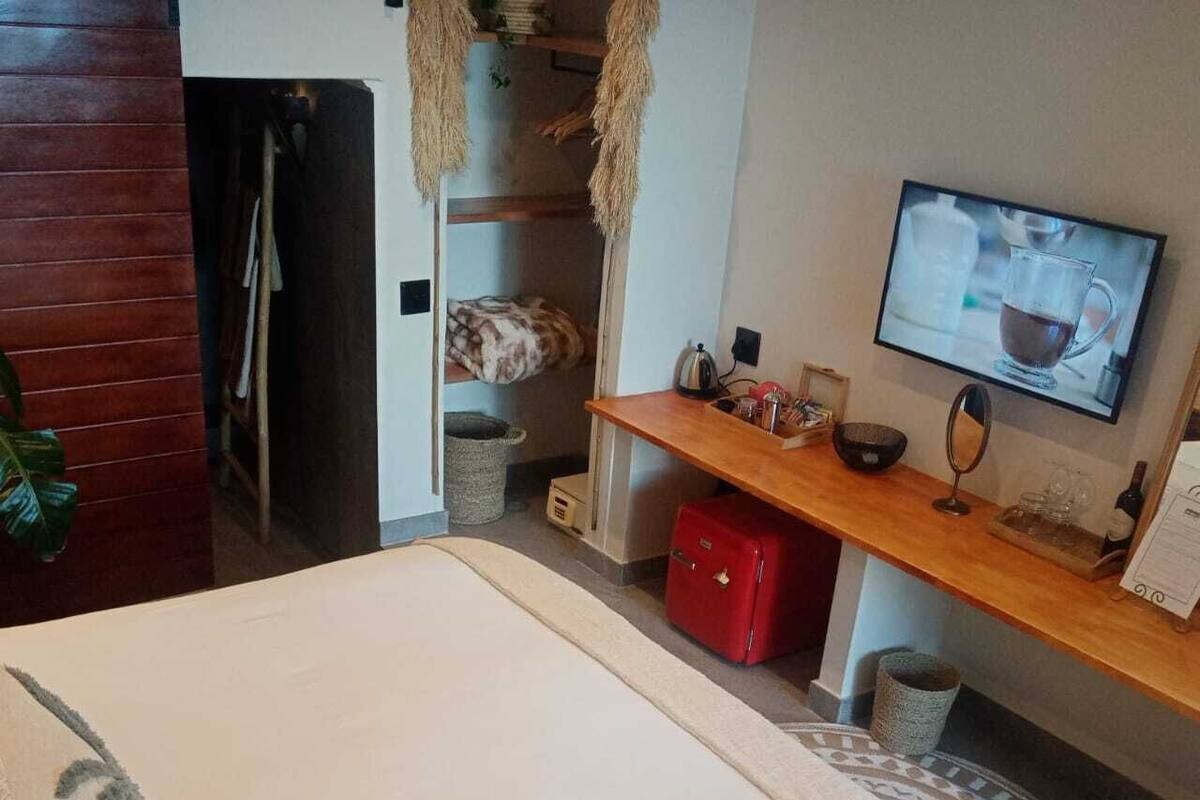 Makuuhuoneessa on sänky, puinen työpöytä, televisio ja pieni punainen kaappi.
