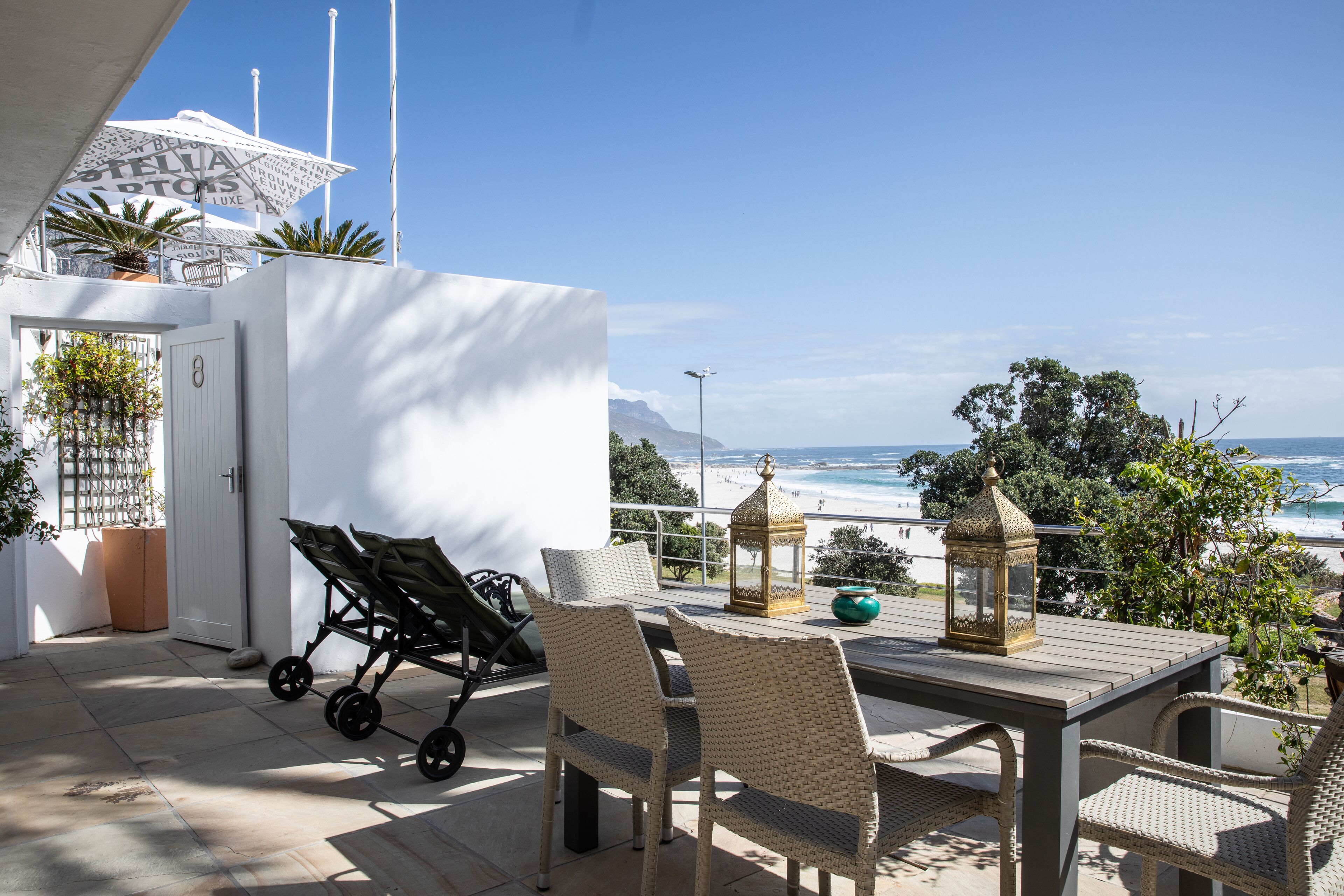 A patio with wicker furniture, a stroller, and a view of the beach.