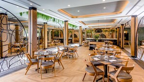 Un restaurante moderno con muebles de madera, plantas verdes y un suelo con estampado de espiga.
