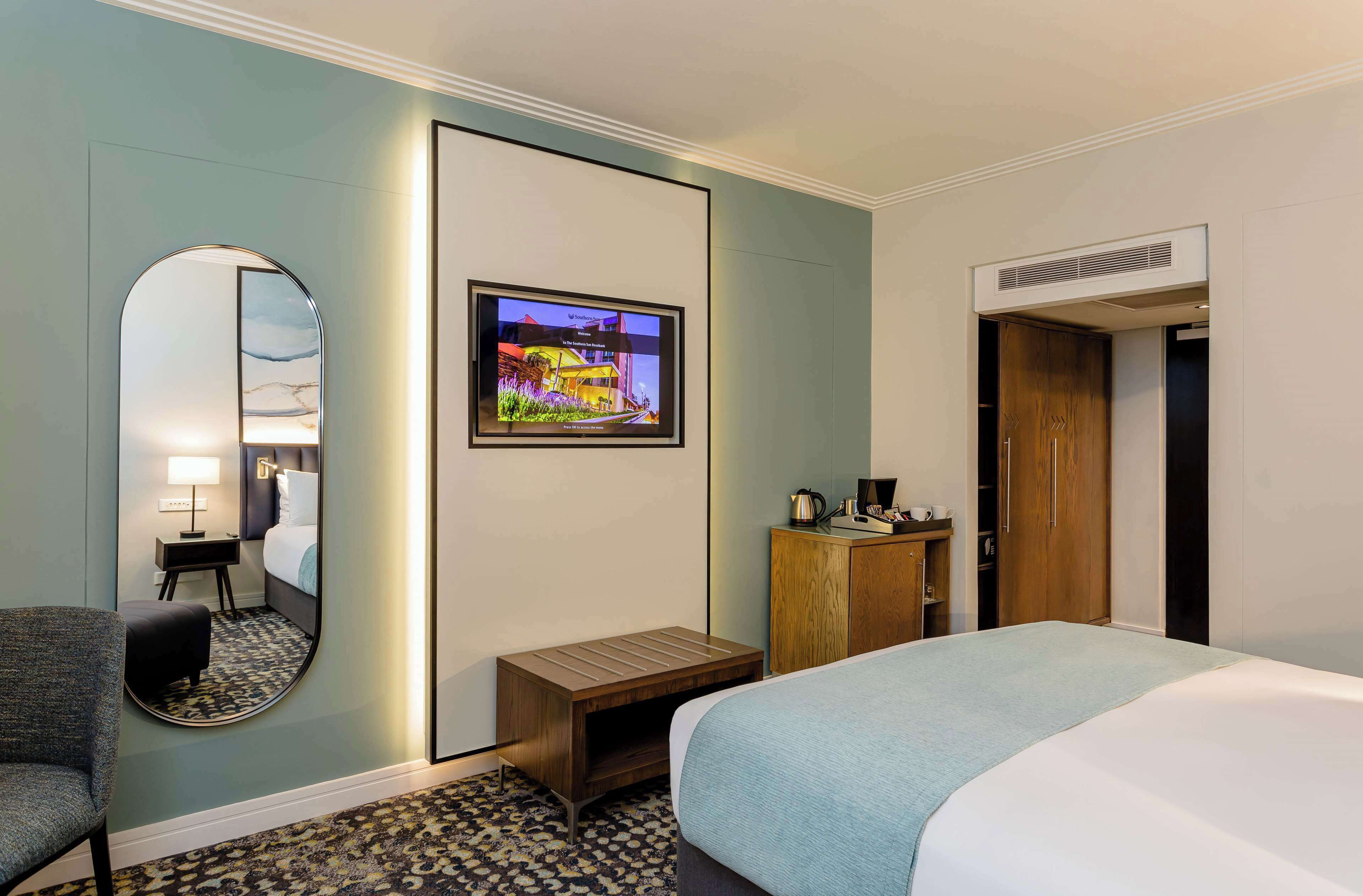 Une chambre d’hôtel équipée d’un lit, d’un bureau, d’une chaise, d’une télévision et d’une armoire.