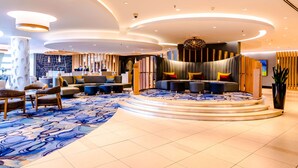 Un lobby moderno con una zona de estar circular, una alfombra estampada y diferentes opciones de asiento.