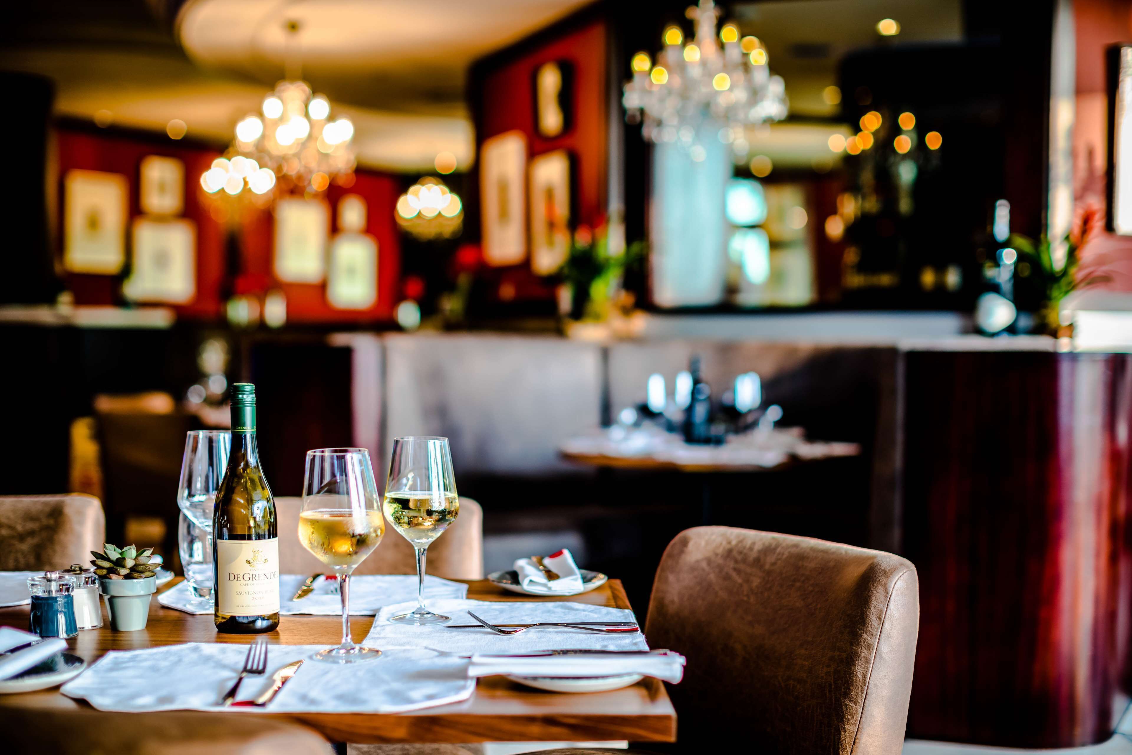 A restaurant interior with a table set for dining, featuring a bottle of wine and glasses.