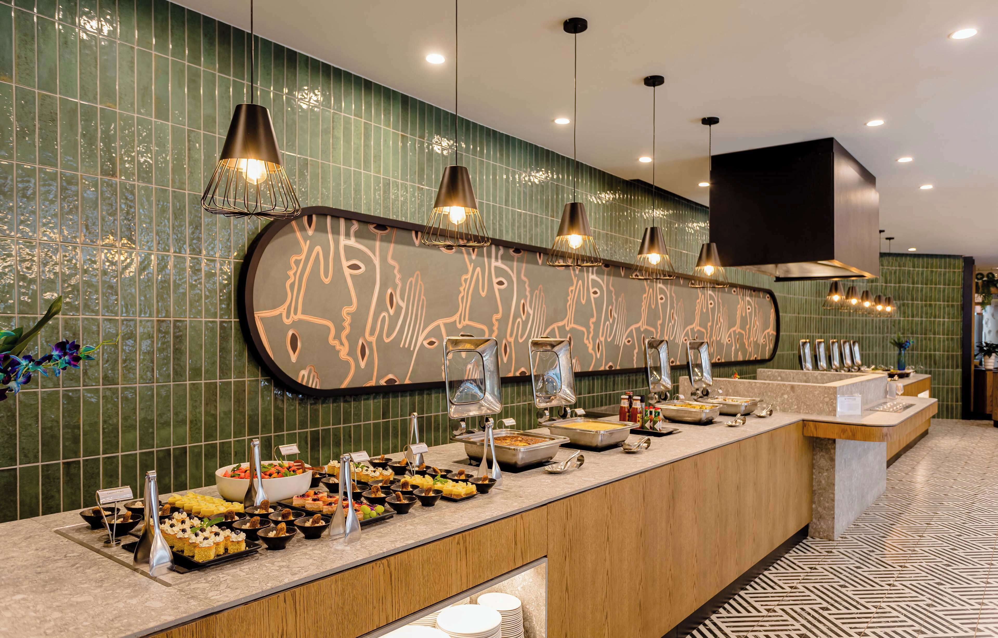 A buffet setup with various food items and a decorative wall.
