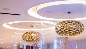 Un área de estar moderna con asientos circulares, lámparas colgantes decorativas y un diseño de pared con motivos.