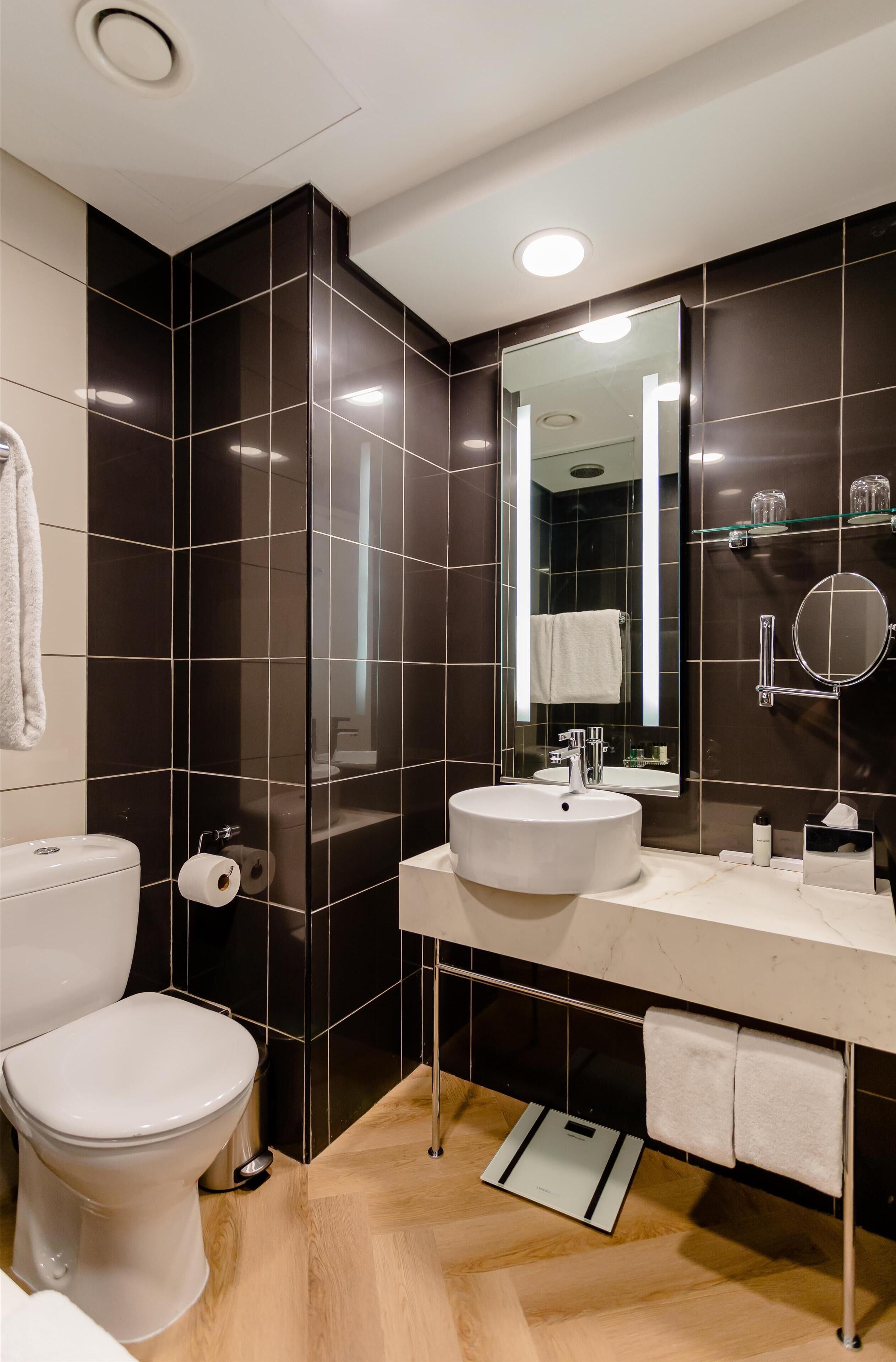 A modern bathroom with a white toilet, a sink, and a mirror.
