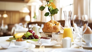 A breakfast setting with croissants, fruits, and beverages on a table. - Hirsch Hotel (Ostfildern)