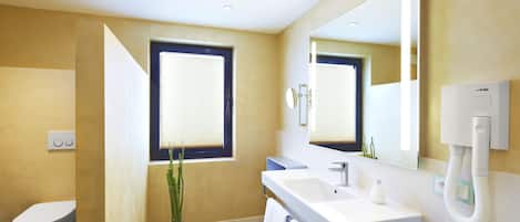 Un baño moderno con inodoro, lavamanos, espejo y ventana.