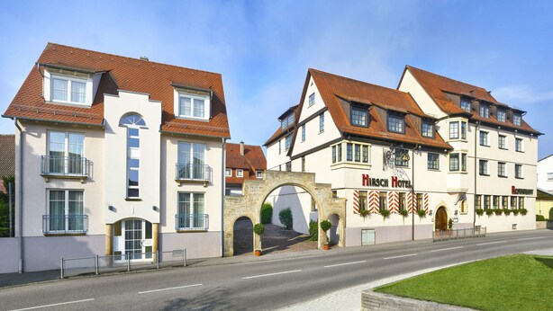 Un hotel de estilo arquitectónico europeo tradicional, con una entrada de arco de piedra y varios ventanales.