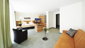 Una habitación de hotel moderna con una cama, un escritorio, un televisor, un sofá y una mesa de centro.