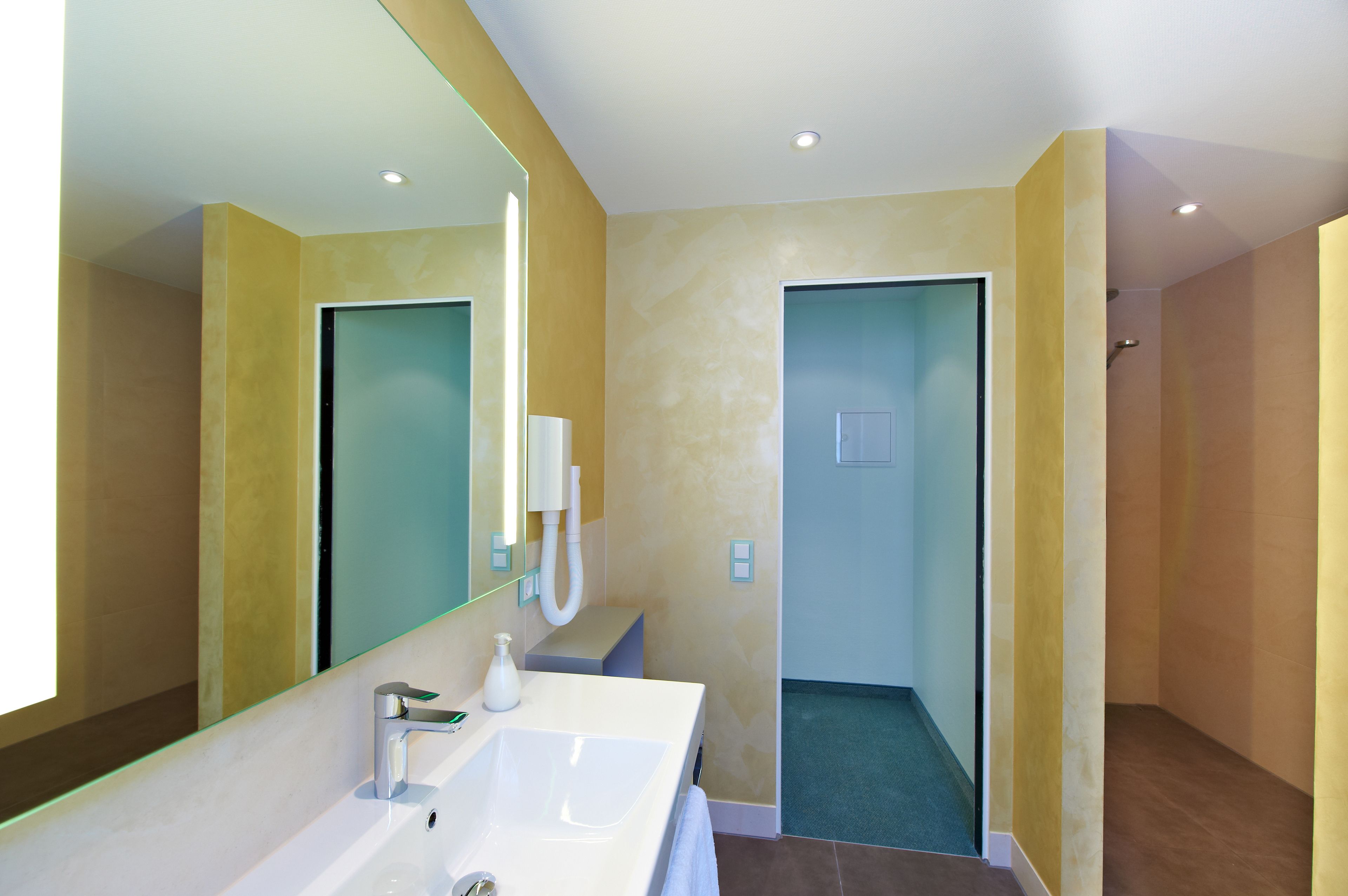 A modern bathroom with a large mirror, a sink, and a shower area.