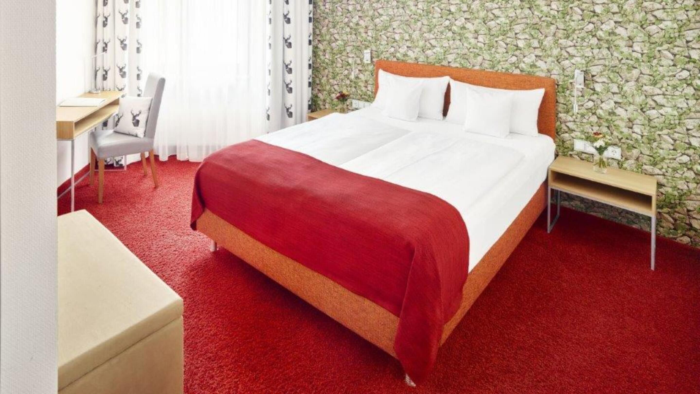 A hotel room with a bed, a desk, and a chair.