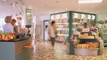 A hotel lobby with a reception desk, a magazine rack, and a tiled floor.
