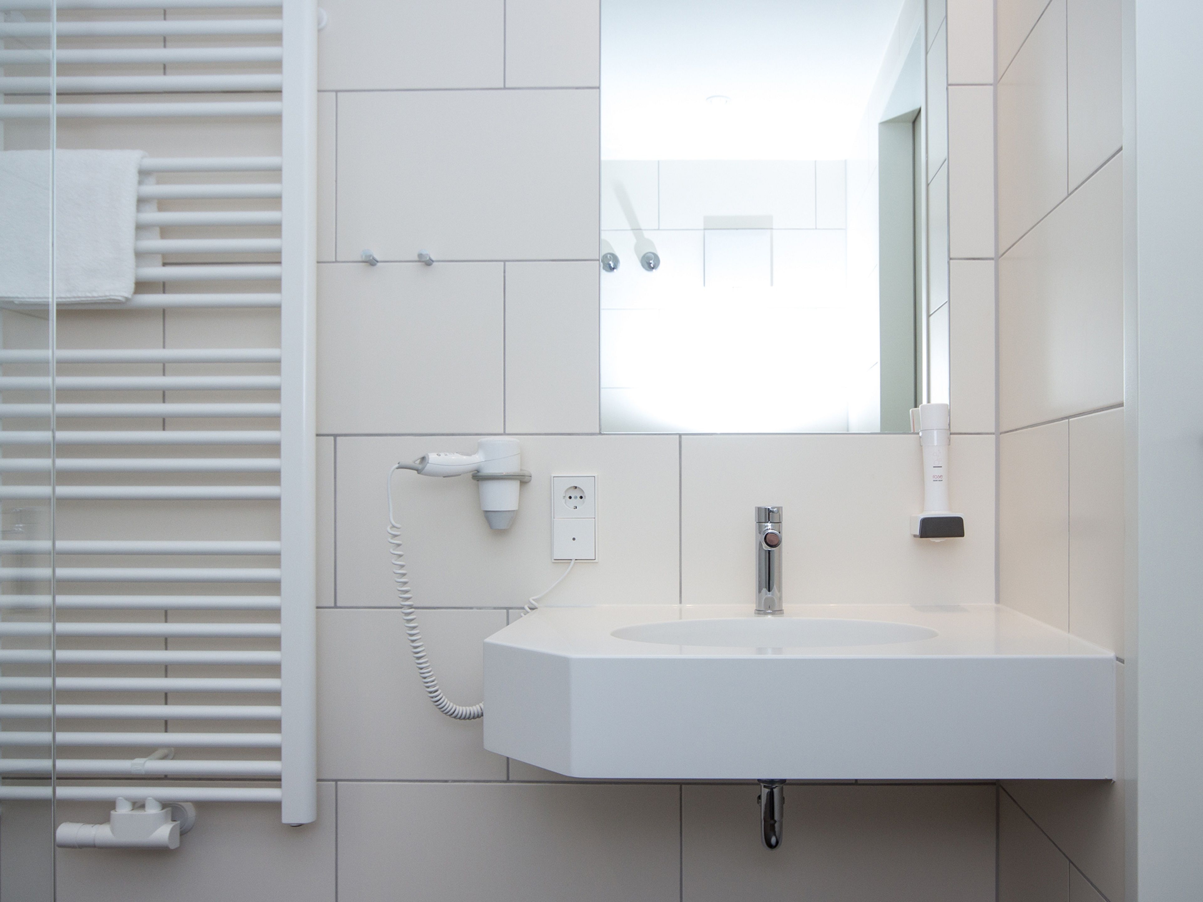 Une salle de bain avec un lavabo blanc, un miroir et un porte-serviettes.