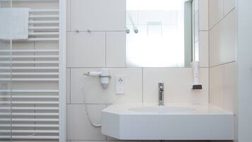 Een badkamer met een witte wastafel, een spiegel en een handdoekhouder.
