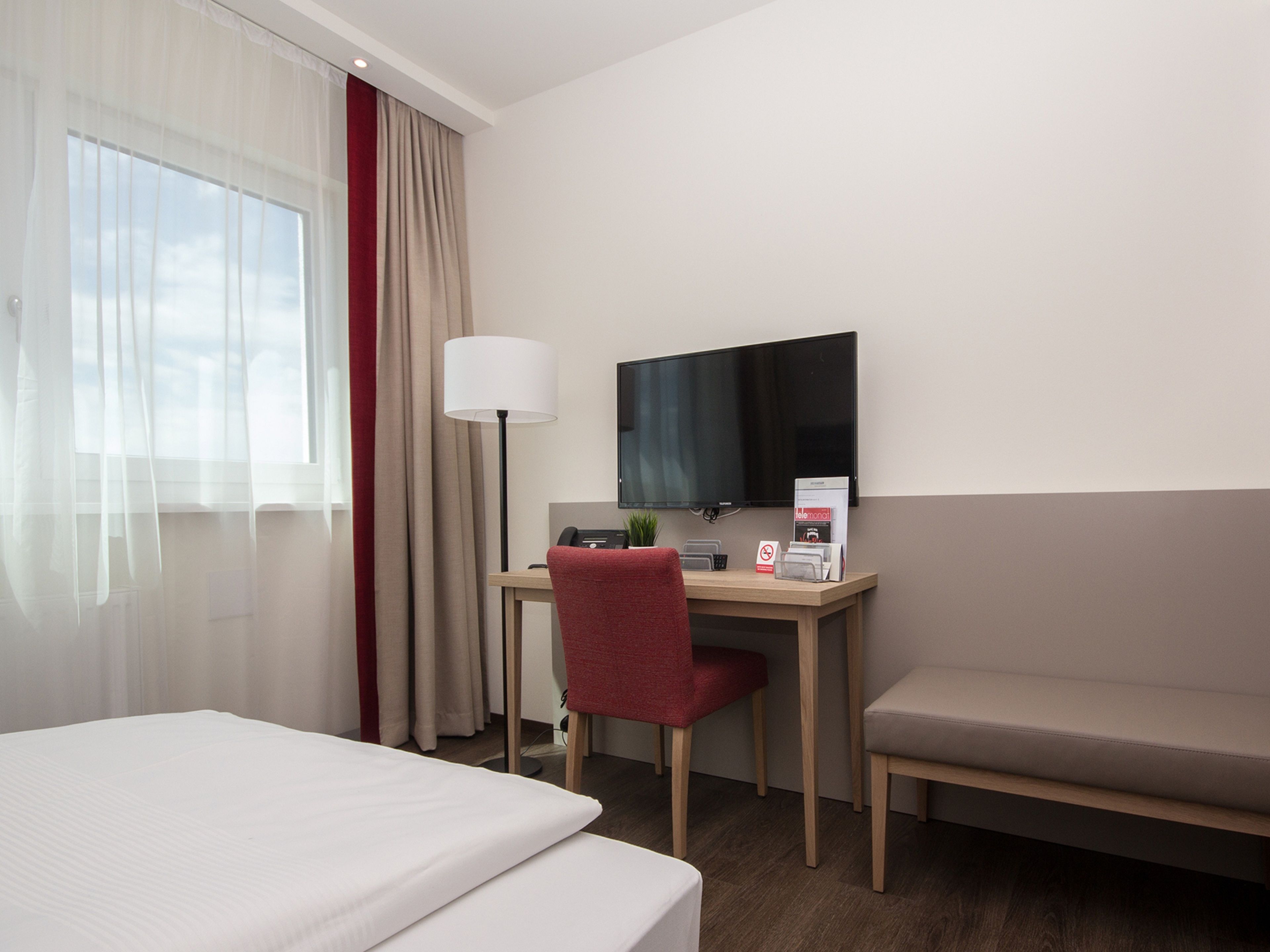 Une chambre d’hôtel comprenant un lit, un bureau avec une chaise, une télévision et un canapé.