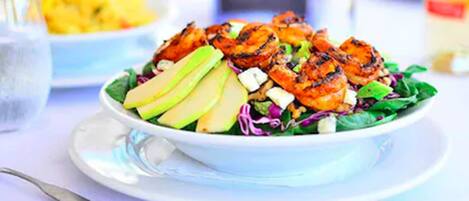 A bowl of salad with grilled chicken, avocado, and mixed greens.