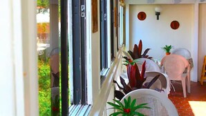 A balcony with a view of greenery, a table with chairs, and a potted plant. - Bunker Hill Hotel (St. Thomas)