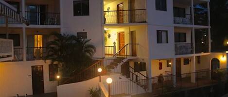 A multi-story hotel with balconies, a swimming pool, and outdoor lighting.