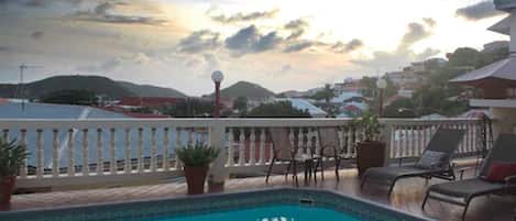 Een buitenzwembad, ligstoelen bij het zwembad