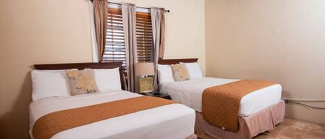 A hotel room with two beds, a nightstand, a lamp, and an air conditioning unit.