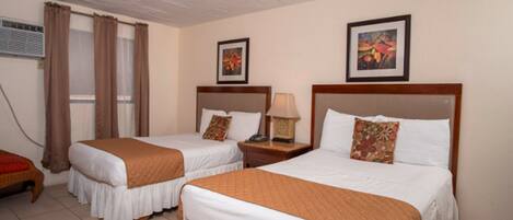 A hotel room with two beds, a nightstand with a lamp, and a window with curtains.