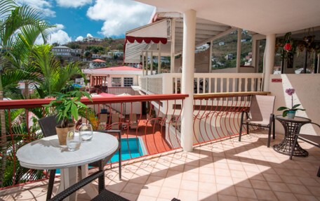 A balcony with a pool, chairs, and potted plants.