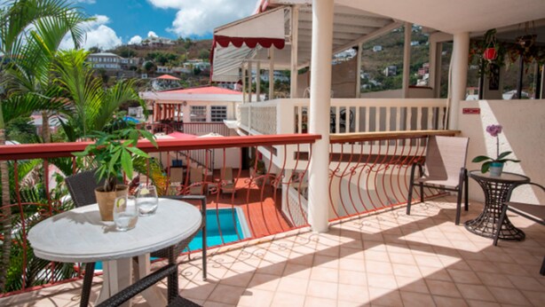 A balcony with a pool, chairs, and potted plants. - Bunker Hill Hotel (St. Thomas)