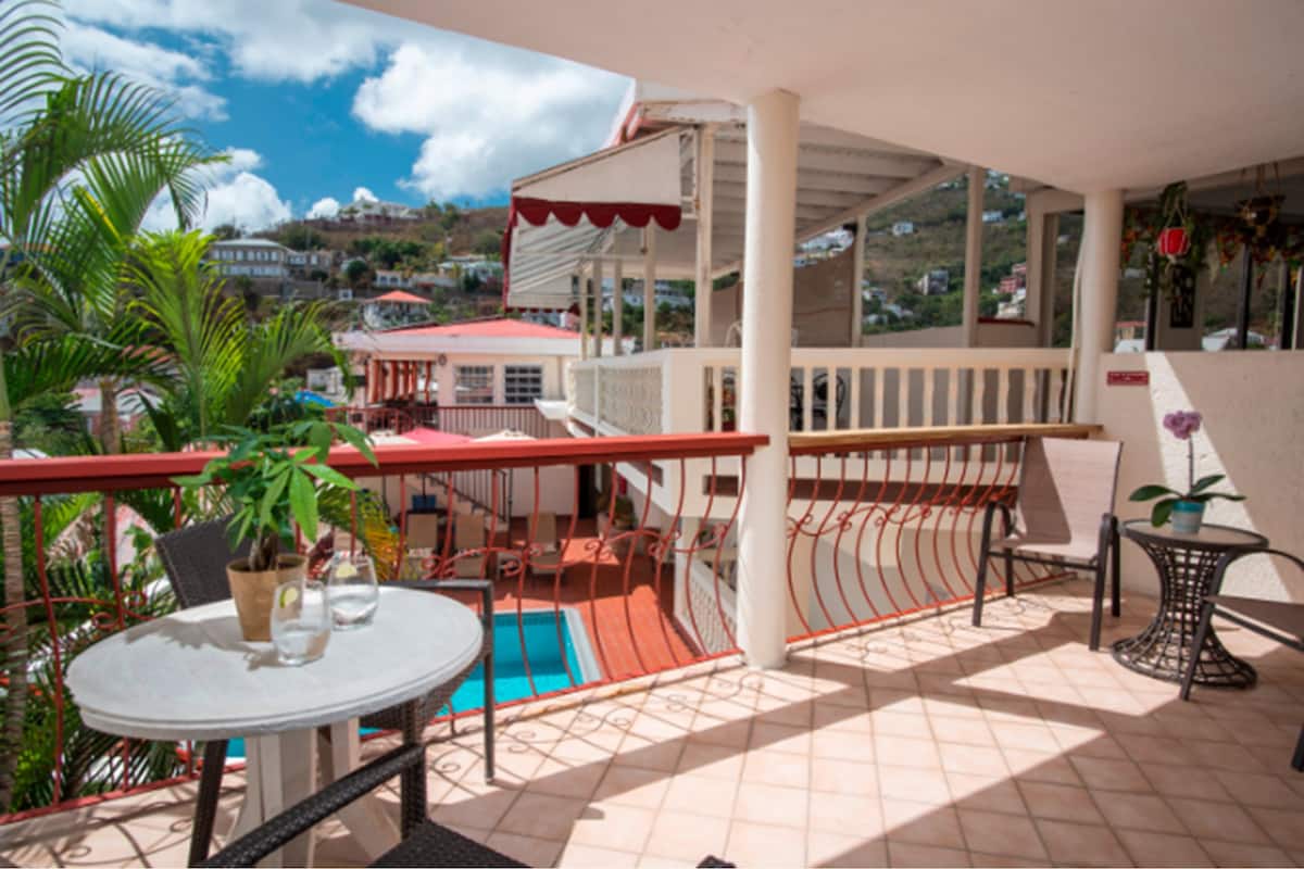 A balcony with a pool, chairs, and potted plants.