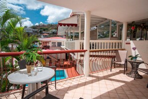 A balcony with a pool, chairs, and potted plants.