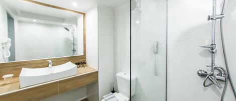 A modern bathroom with a glass-enclosed shower, a white sink with a wooden countertop, and a toilet with a towel on the seat.