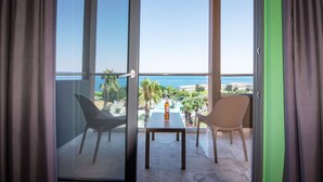 Een balkon met een tafel en twee stoelen, met uitzicht op een zwembad en palmbomen.