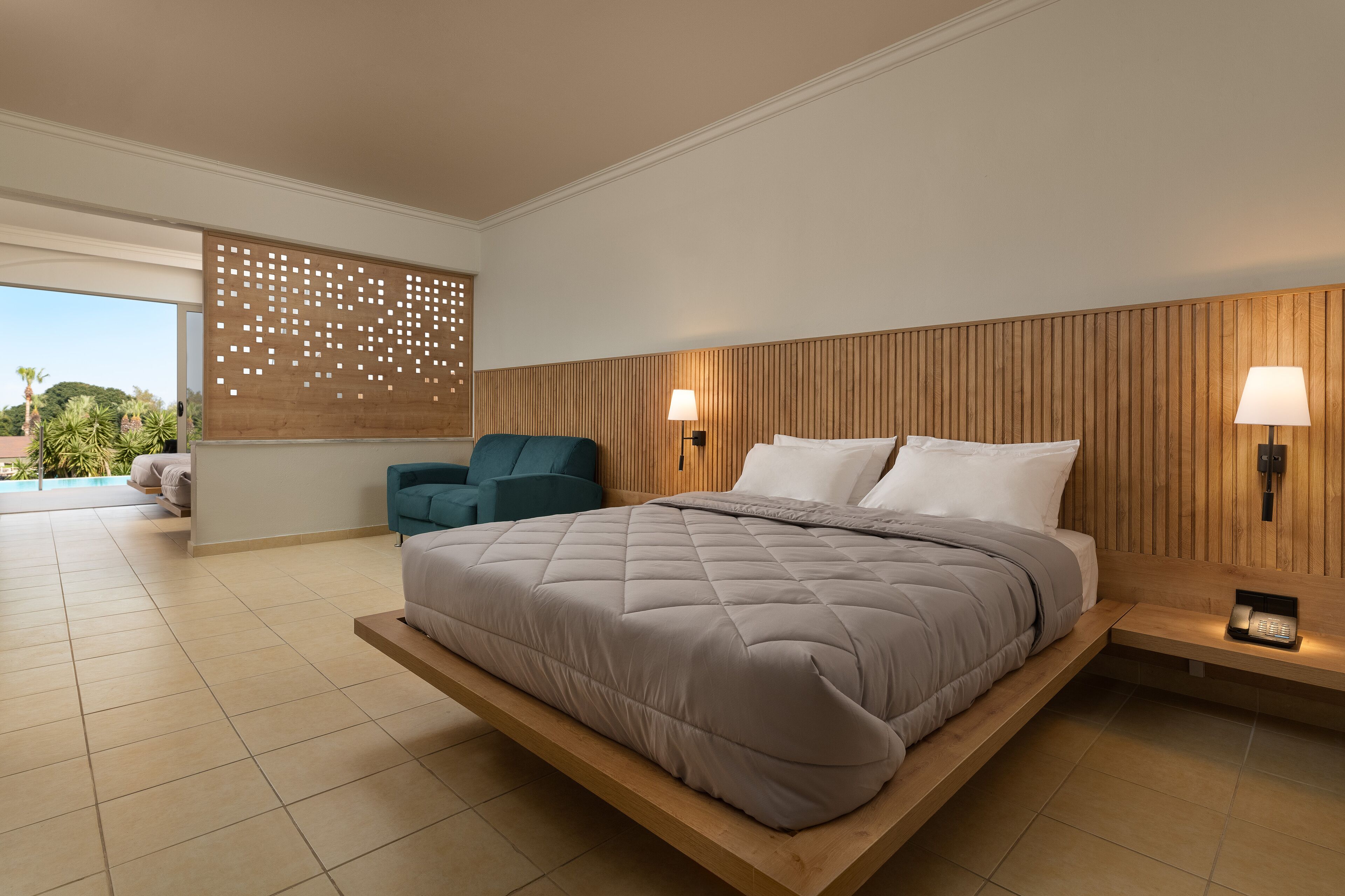 A modern bedroom with a large bed, a seating area, and a view of the outdoors.