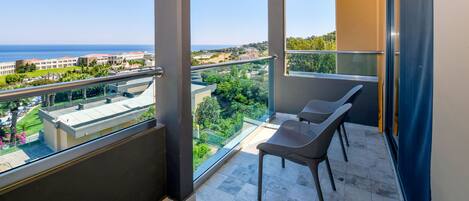 Un balcón con vistas al mar y edificios, que incluye una silla y una mesa.