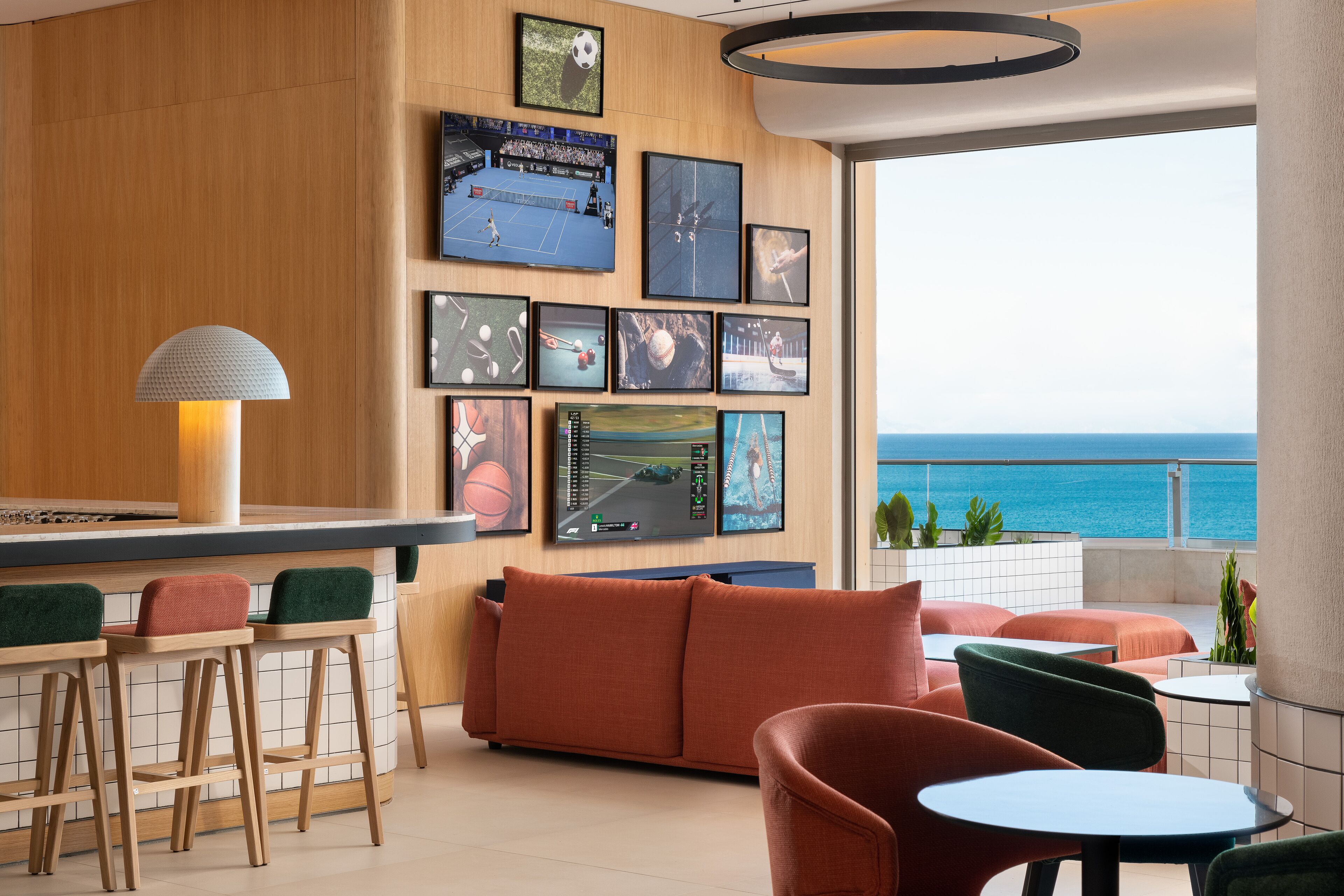 A modern lounge area with a bar, seating, and a large wall of sports memorabilia.