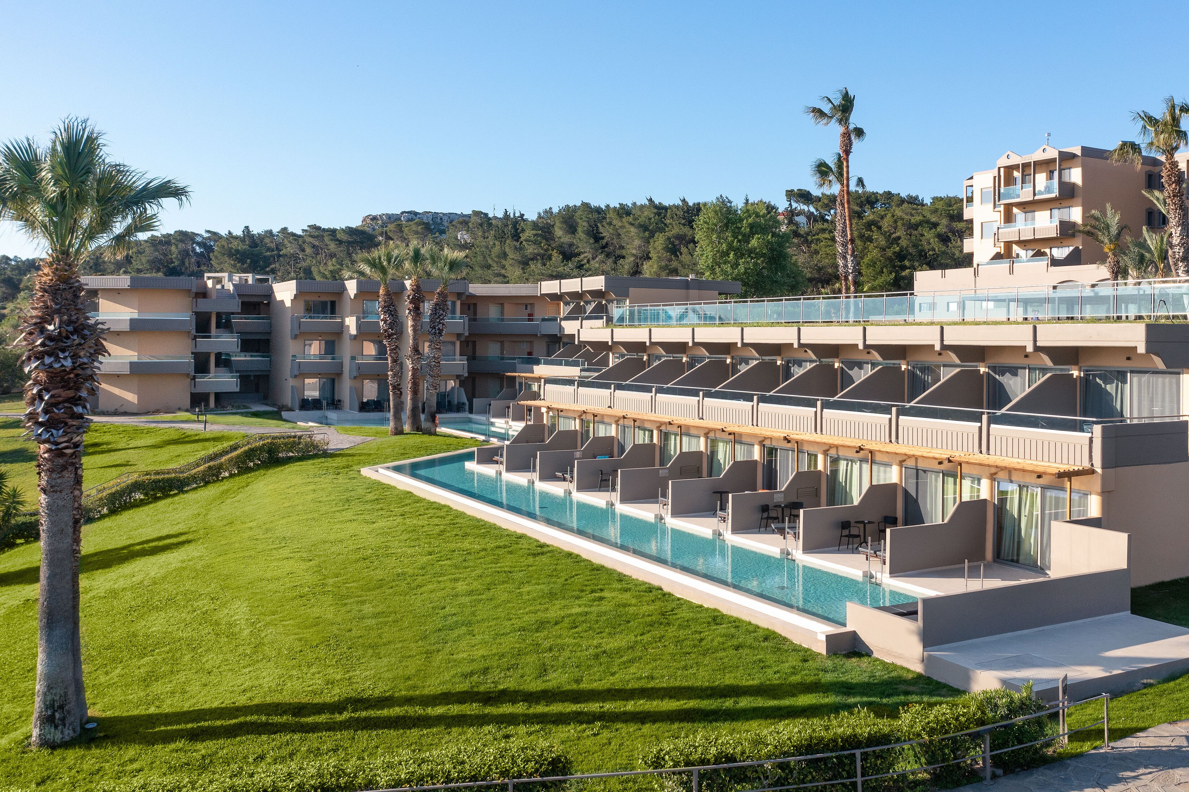Ein Hotel mit mehreren Etagen, einem Schwimmbad und Palmen.