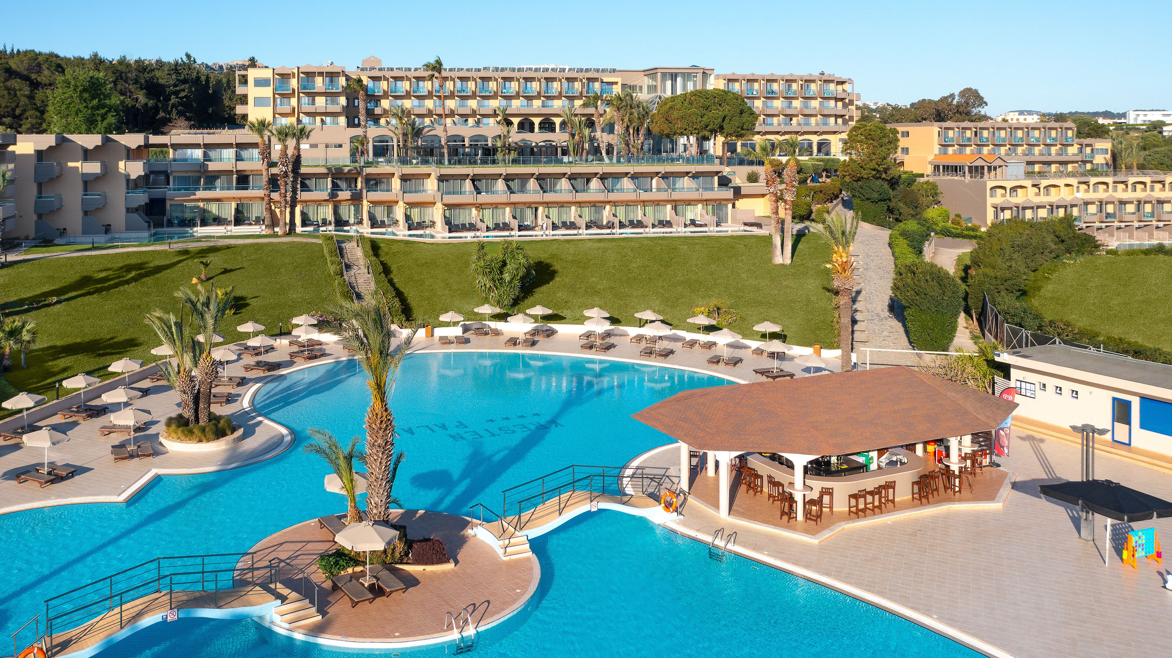 A hotel with a large swimming pool, multiple balconies, and a bar area.