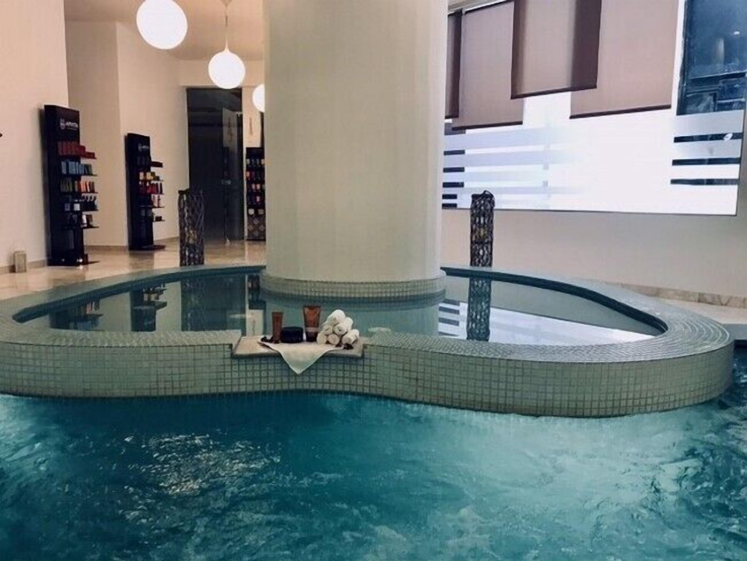 An indoor swimming pool with a tiled edge, a towel, and toiletries on the edge.
