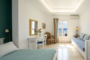 Un dormitorio con cama, escritorio, silla, sofá y vistas al mar.