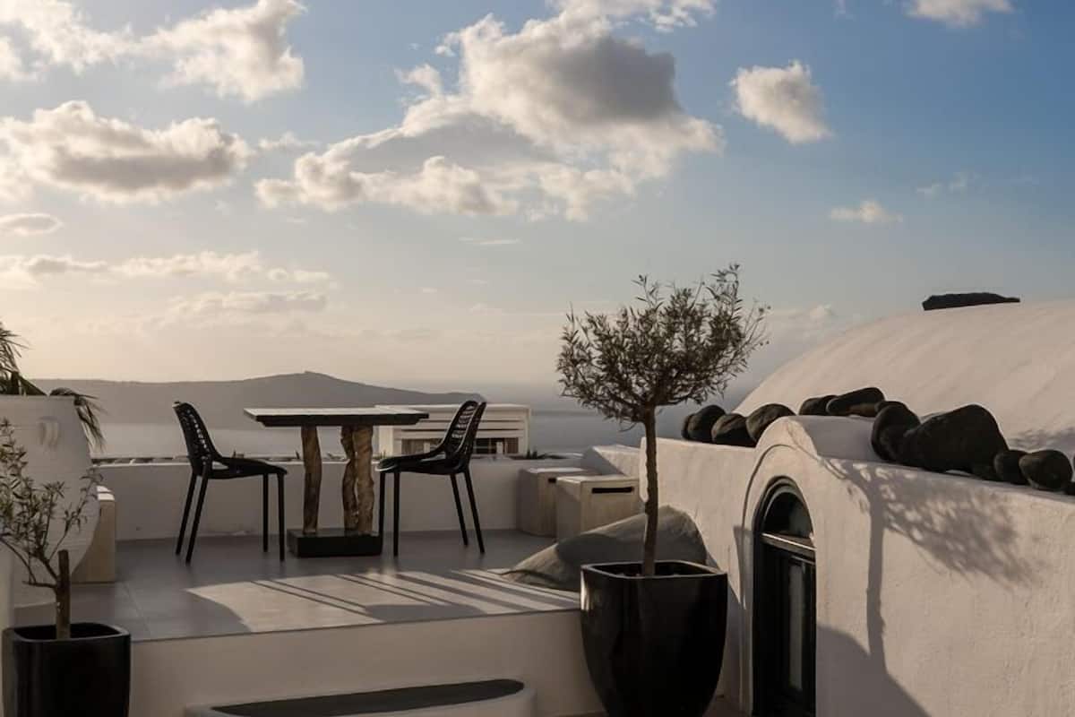 Terraço no telhado com mesa, cadeiras, uma pequena árvore e área de estar.