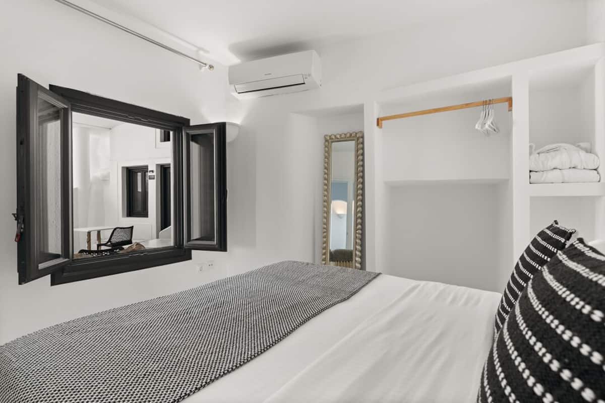 Quarto com cama, um espelho grande, guarda-roupa e ar condicionado.