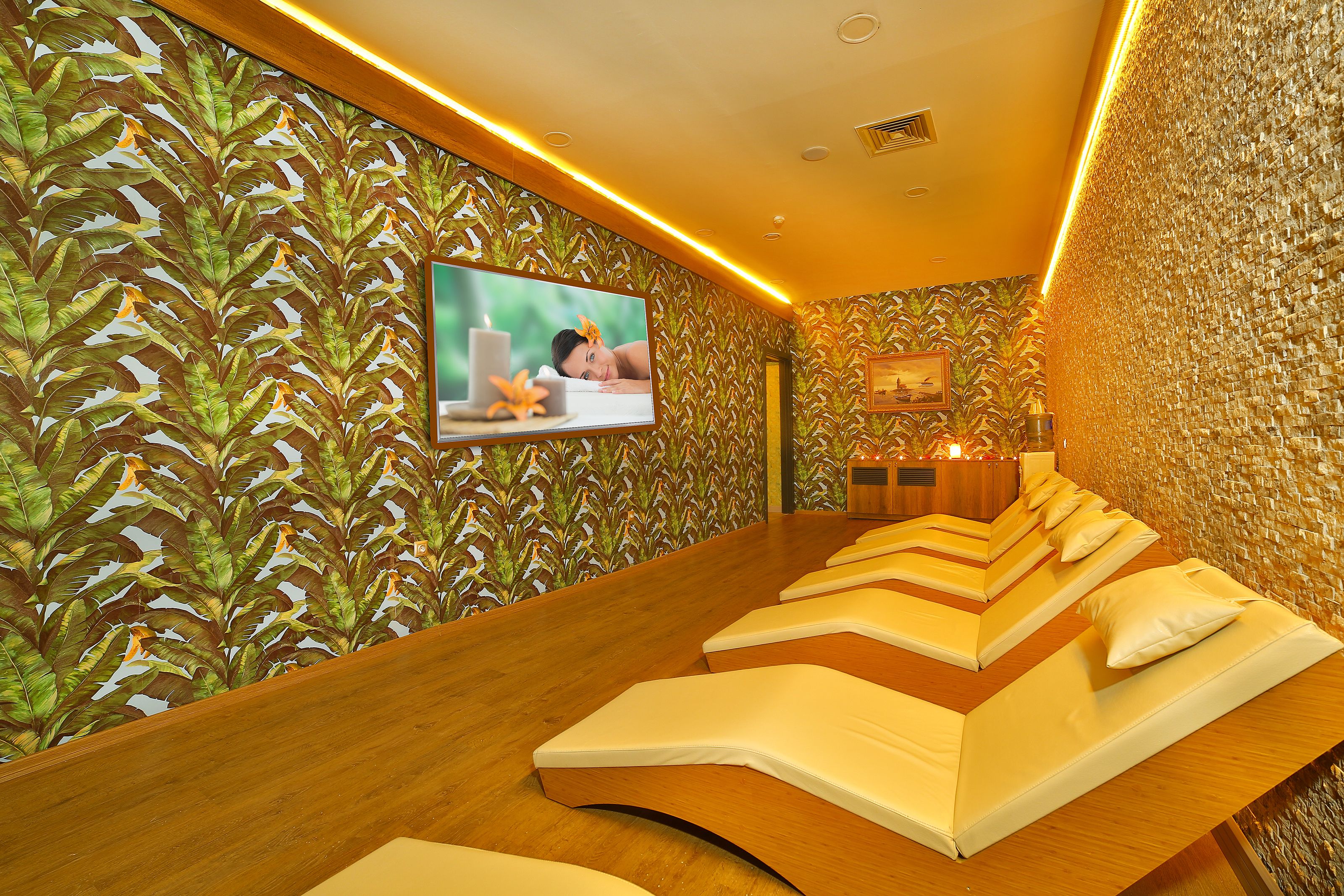 Une salle de spa équipée d’une table de massage en bois, d’un écran de télévision et d’un mur décoré de motifs.