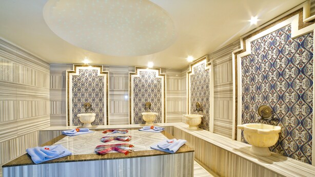 Un baño lujoso con tocador de mármol, varios lavamanos y azulejos decorativos.