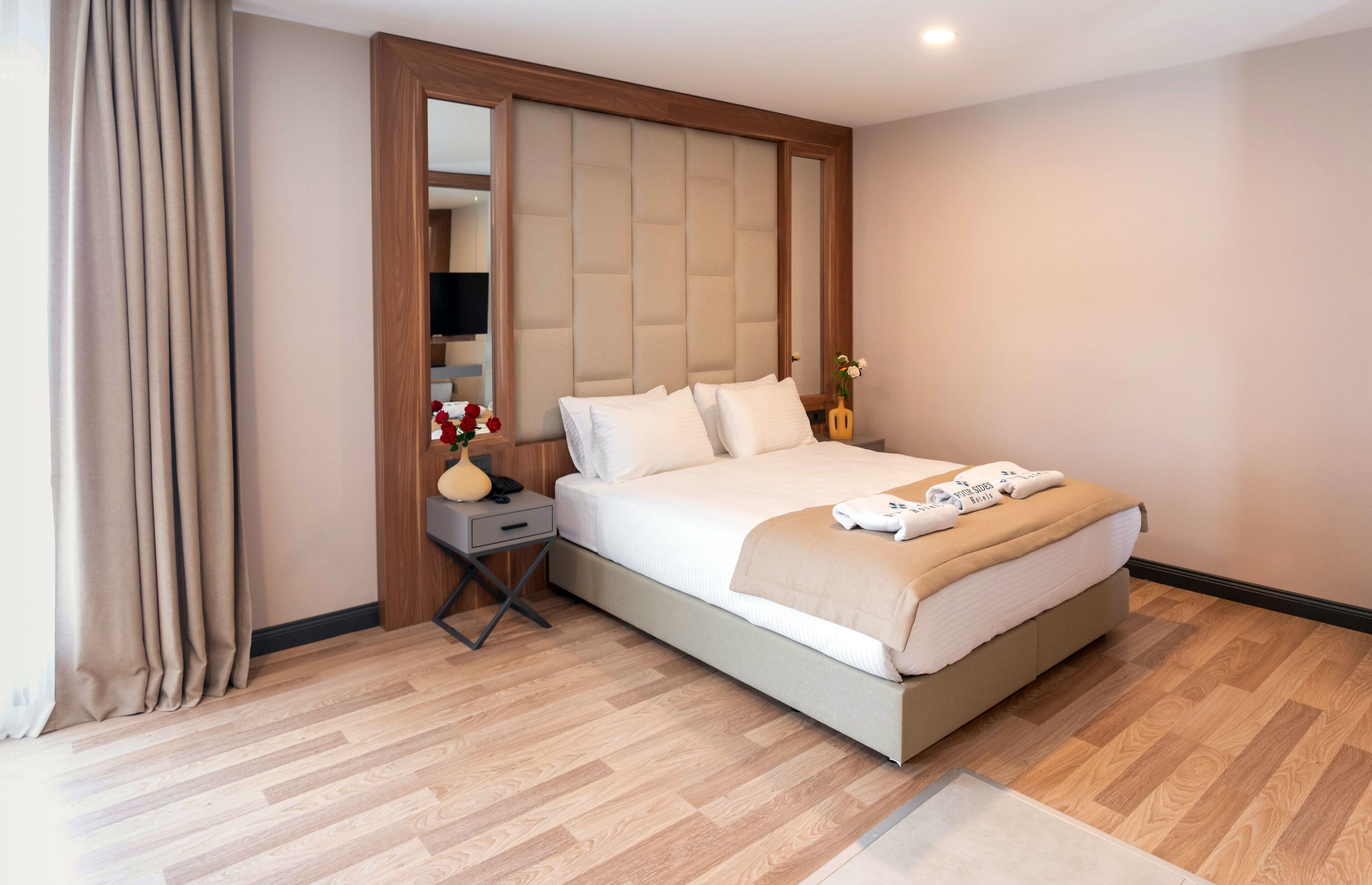 A hotel room with a large bed, a nightstand, a mirror, and a wooden headboard.