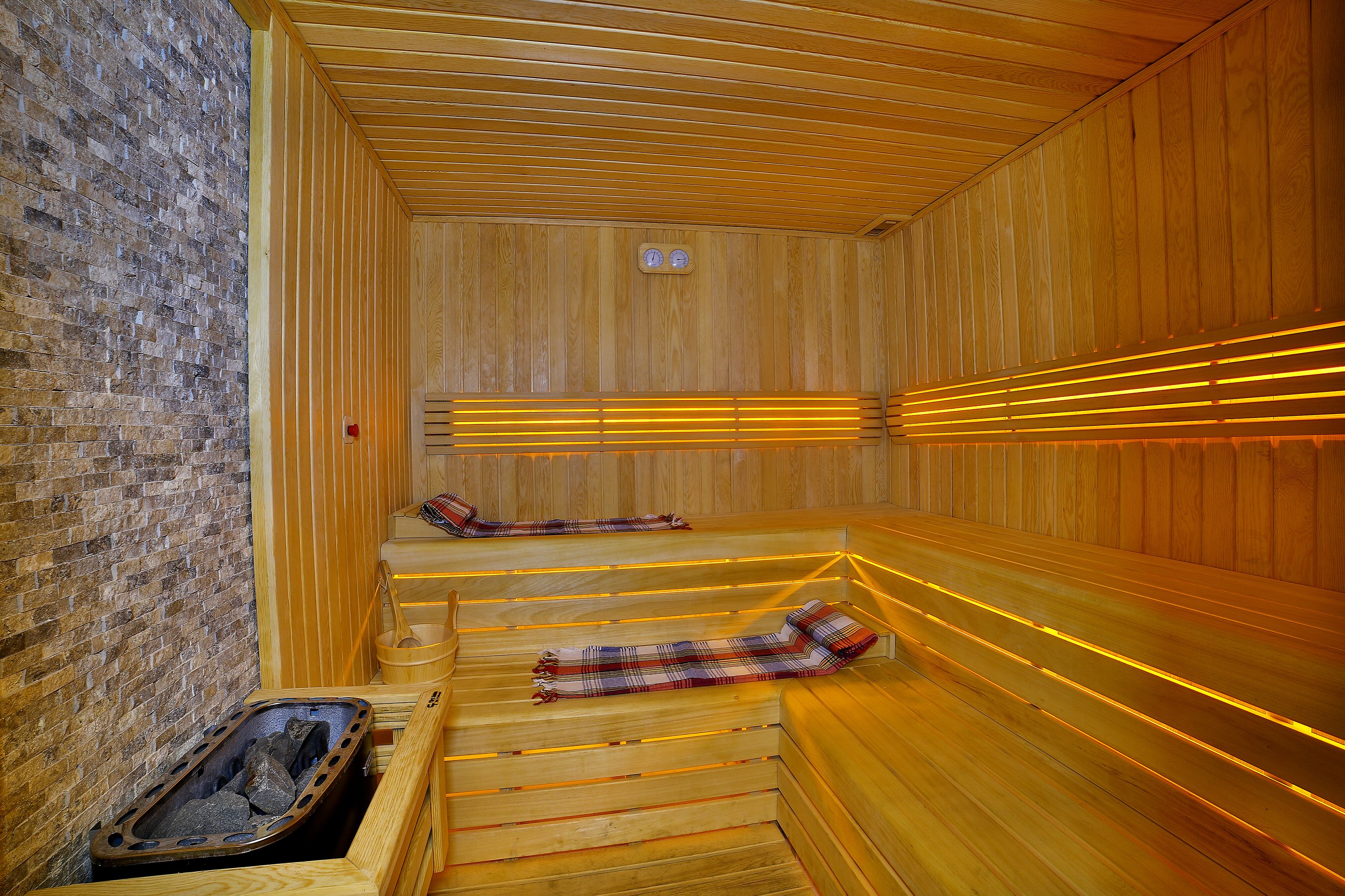 Un sauna avec des bancs en bois, un mur en briques et un plafond en bois.