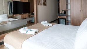 Une chambre d’hôtel avec un grand lit, une télévision, un minibar et une armoire.
