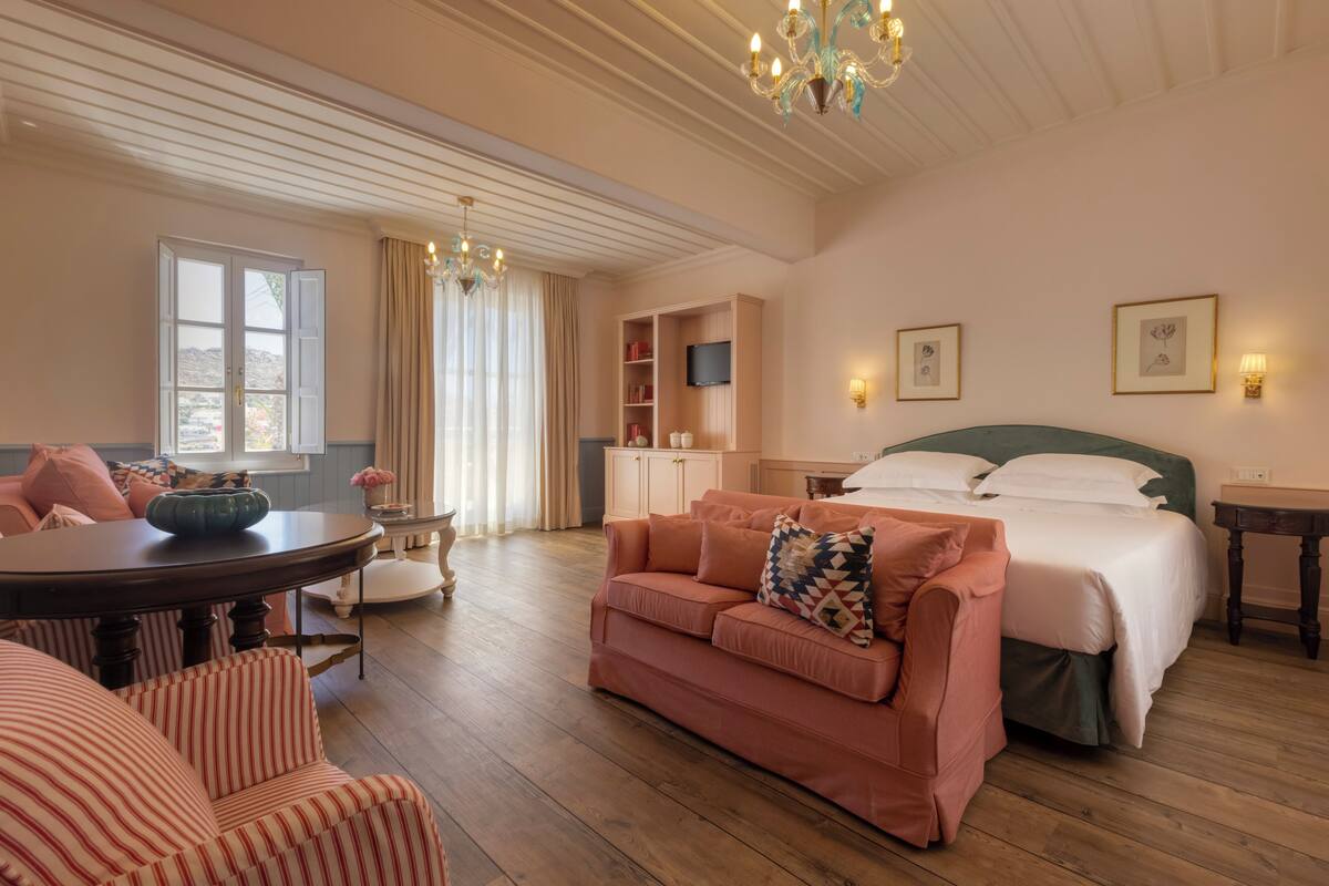 A cozy room with a bed, a sofa, a dining table, and a TV.