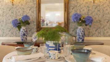Une table à manger dressée avec de la vaisselle bleue et blanche à motifs, comprenant des bols, des tasses et un vase avec une plante verte.