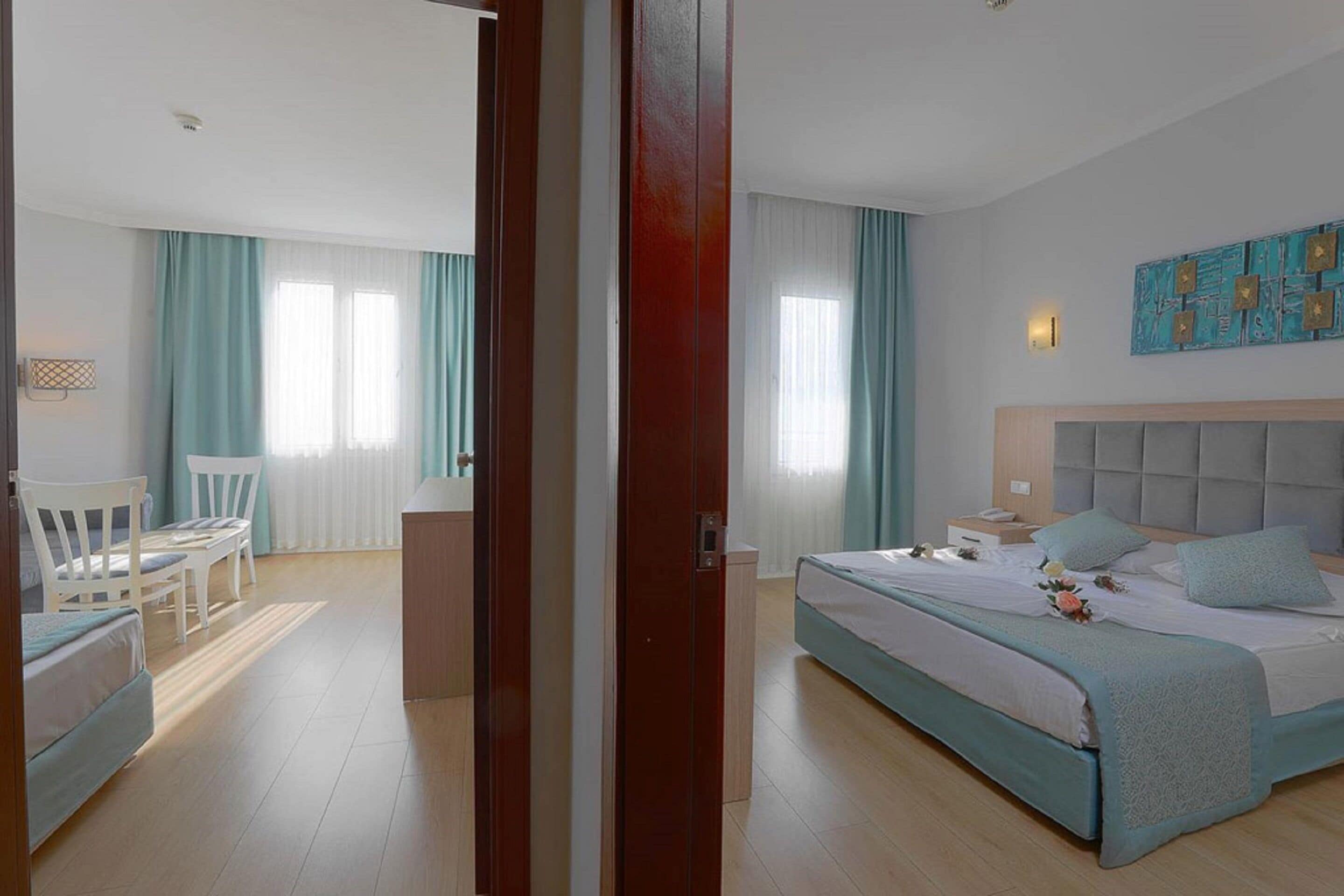 A hotel room with a bed, a desk, a chair, and a window with curtains.