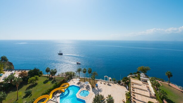 Un resort con piscina, palmeras y vista al océano.