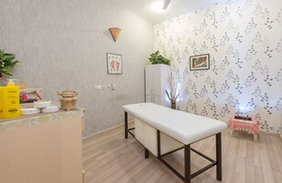 Ein Zimmer mit Holzboden, einer weißen Bank, einem Schrank und einer Wand mit Blätermotiv.